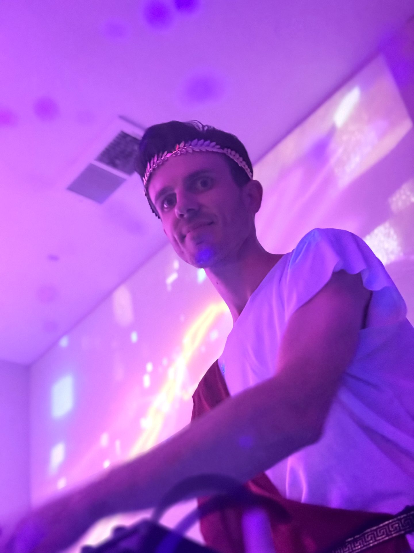 A close-up behind the decks with purple projection lighting