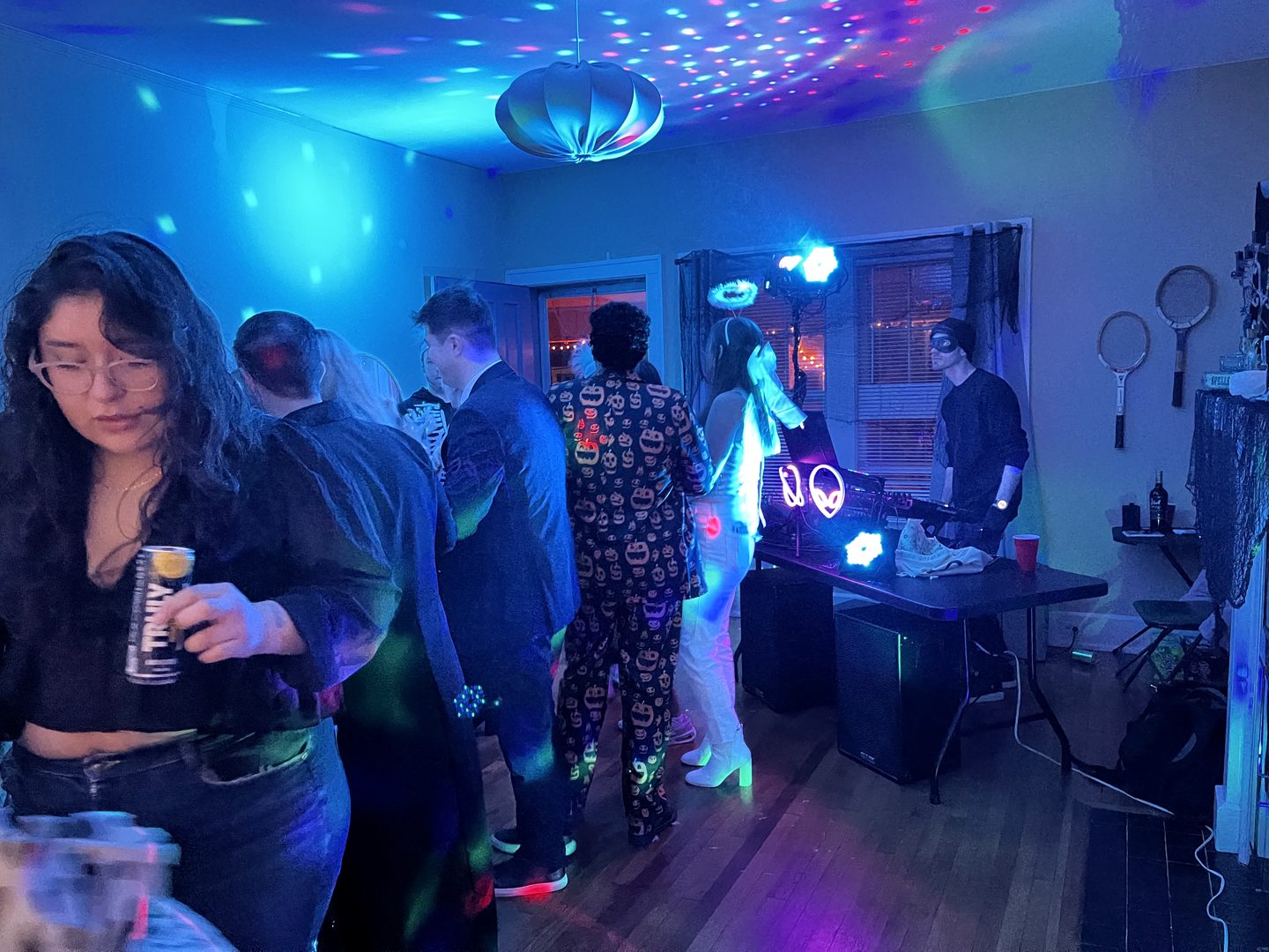 Guests gathered in a room lit with cyan and purple party lights